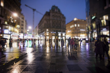 Naklejka premium night and rainy city streets with people walking 