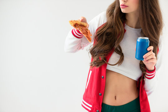 cropped image of sexy girl in baseball jacket holding pizza and can isolated on white