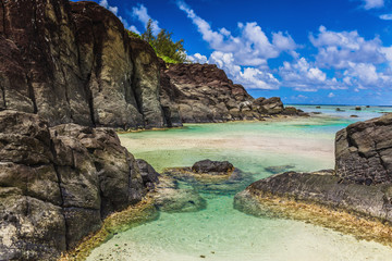 Fototapeta na wymiar Black Rock, tropical beach surrounded by black rocks, Rarotonga, Cook Islands