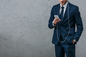 cropped shot of businessman listening music with headphones and smartphone - Powered by Adobe