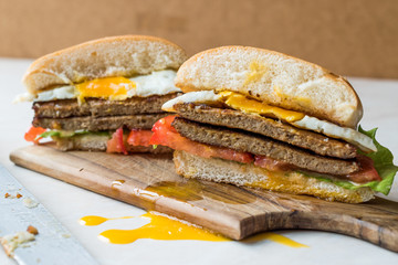 Half Cut Hamburger with Egg, Tomatoes and Lettuce on Wooden Surface.