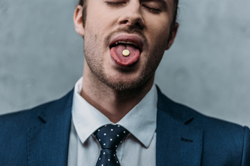 close-up portrait of addicted businessman sticking out tongue with mdma pill