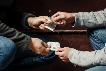 Hand of addict man with money buying dose of cocaine or heroine or another narcotic from drug...