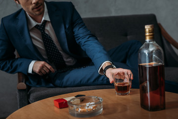 cropped shot of businessman taking glass of whiskey from table
