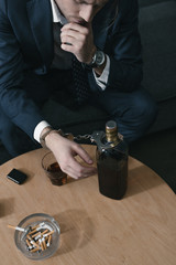 alcohol addicted businessman with glass and bottle of whiskey