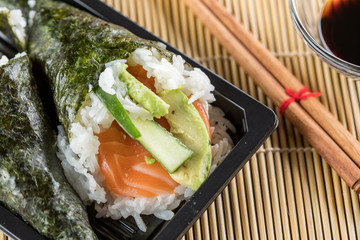 Zwei Lachs Avocado Gurken Temaki Sushi in Bento Box mit Stäbchen und Sojasauce