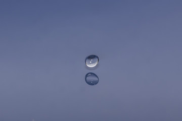 drop of water liquid with splash isolated. the drop explodes in the water sending spray to the sides and circle ripples around it. the water is blue