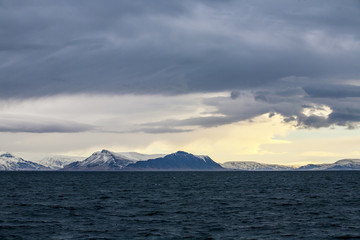 Evening Island coast with the dramatic sky and the snow mountain in the background