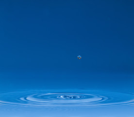drop of water liquid with splash isolated. the drop explodes in the water sending spray to the...