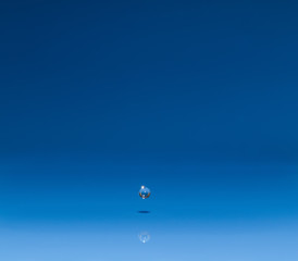 drop of water liquid with splash isolated. the drop explodes in the water sending spray to the sides and circle ripples around it. the water is blue