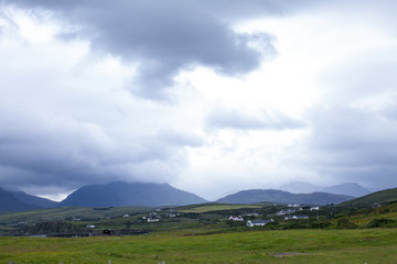 Nature meadow panorama with the small village before the rain in Ireland