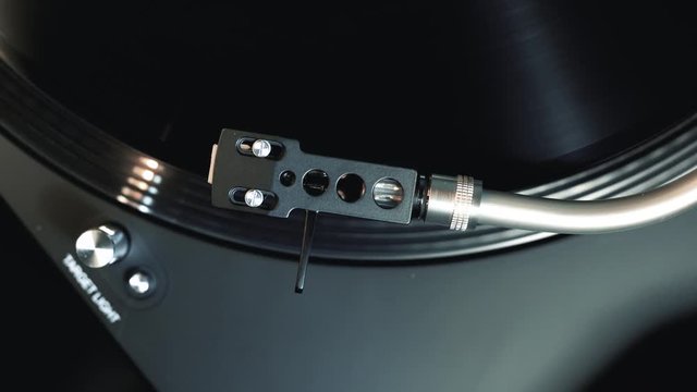 Hand putting the needle of a turntable on a record, top view