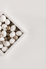 top view of chicken and quail eggs in box, isolated on white
