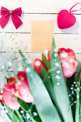 Red live tulips on a white wooden background