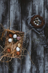 Fototapeta na wymiar Painted chicken eggs and quail eggs in nest on table