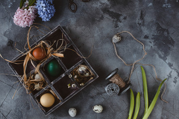 Easter eggs in wooden box with hyacinths on slate background