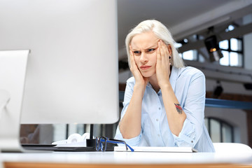 Ból głowy i zmęczenie w pracy.
Zmęczona kobieta pracuje przy komputerze.
 - obrazy, fototapety, plakaty