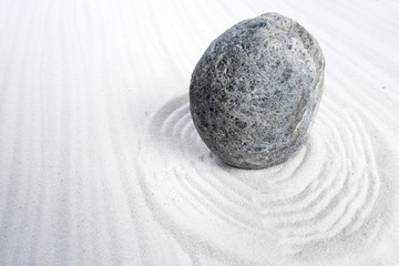Fototapeta na wymiar Zen garden stone with curves on sand