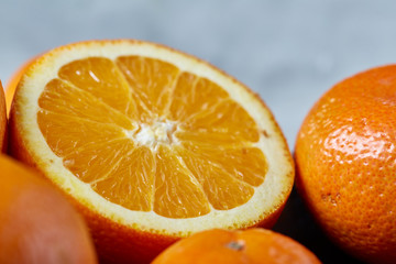 Close-up of whole and half cut fresh tangerine and orange on cutting board over white background, shallow depth of field