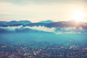 some mountains with villages on the bottom and sun in the sky