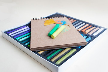 Pastel crayons  and notebook on a light background.