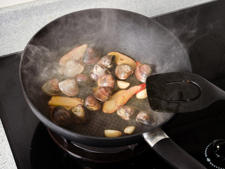 Stir-frying Ginger and clams at high heat to bring forth the savory aroma with sesame oil in recipe