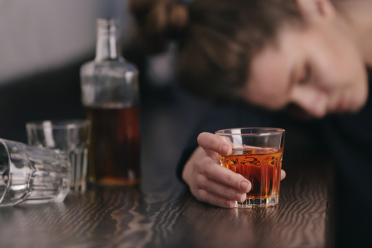 Unconscious drunk woman with glass of drink in bar, closeup. Alcoholism problem