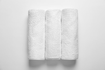 Rolled clean terry towels on white background, top view