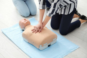 Group of people practicing CPR on mannequin at first aid class