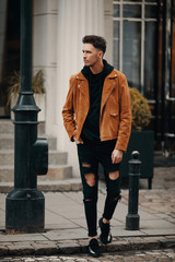 Model looking man stand on the city street with cars background, look on his watch and around