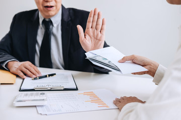Bribery and corruption concept, senior businessman manager refusing receive money in the envelope to agreement contract, A bribe in the form of dollar bills