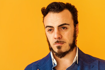 Man closeup portrait wearing blue jacket on yellow background