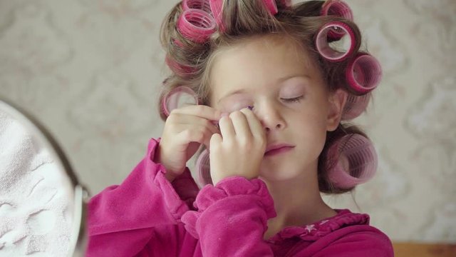 Girl with pink curlers doing makeup