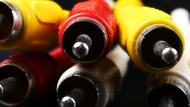 red, white and yellow male cinch plugs, on black background