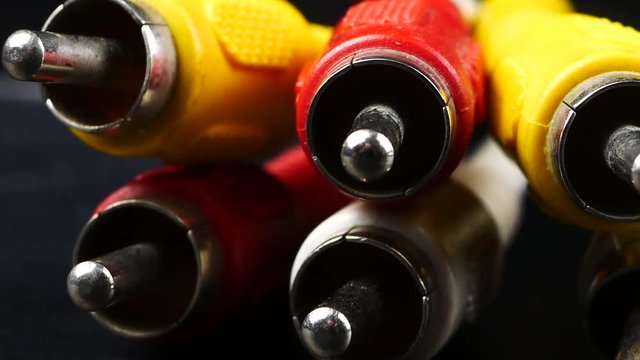 red, white and yellow male cinch plugs, on black background