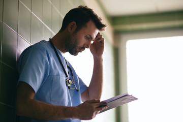 Stressed doctor reading medical documentation, worried about patient