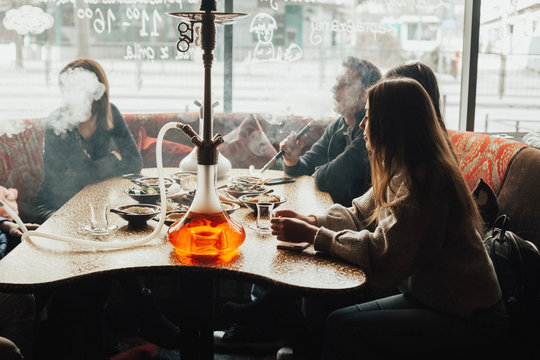 A young company of people is smoking a hookah and communicating in an oriental restaurant. Lebanon cuisine served in restaurant.  Traditional meze lunch