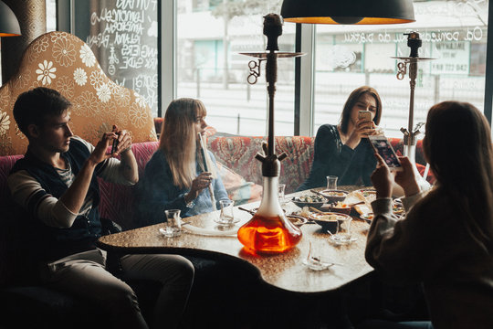 A Young Company Of People Is Smoking A Hookah And Communicating In An Oriental Restaurant. Lebanon Cuisine Served In Restaurant.  Traditional Meze Lunch