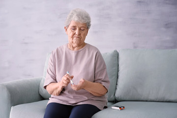 Elderly woman with diabetes measuring level of blood sugar at home