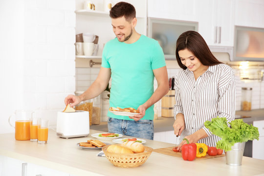 Young couple preparing breakfast with toasts in kitchen