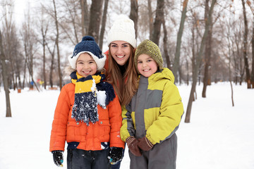Happy woman with sons in snowy park on winter vacation