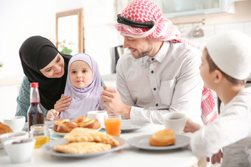 Happy Muslim family having breakfast together at home