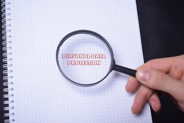Businessman looking at a magnifying glass word:PERSONAL DATA PROTECTION