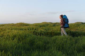 Naklejka na ściany i meble Hiker girl is traveling with a backpack on the landscape background