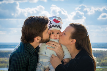 Obraz premium Happy family photography: mom and dad kissing a child