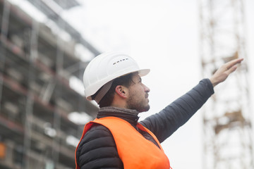 Man with wearing safety vest and hard hat at construction site