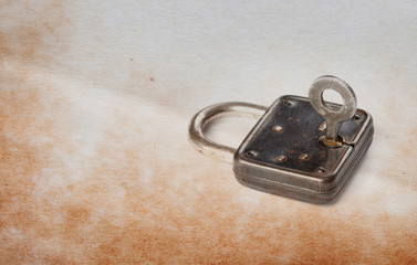 Vintage padlock with key in hole, aged textured paper background. copy space