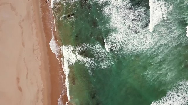 Aerial tilt view on ocean waves, beach and rocks on the Atlantic coast in Morocco, 4k
