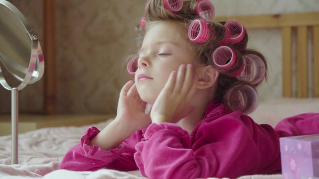 Portrait of little funny girl in curlers