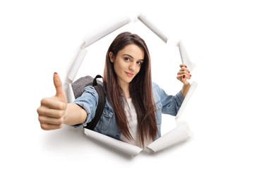 Female teenage student breaking through paper